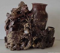 Front view showing carved floral and rock motif with two vessel openings