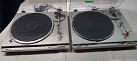 Front view of both Technics turntables with mats and tonearms visible
