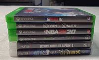 Side view of all six stacked game cases showing titles and platforms