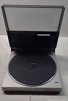 Turntable with dust cover open showing platter and mat
