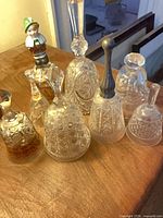 Group shot of all eight glass and crystal bells on wooden surface