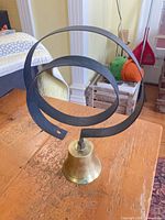 Overall view of brass bell with black steel coil hanger