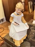 Front view of Amy figurine seated sketching