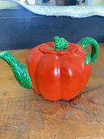 Front view of ceramic pumpkin teapot showing handle, body and lid