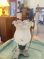 Full view of lamp showing glass shade, metal cherub, base and power cord