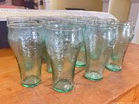 Group of 18 green-tinted Coca-Cola glasses on table