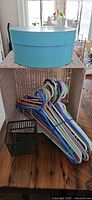 All items together: wicker bin, hat box on top, green basket and bundle of hangers