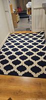 Full view of navy and ivory trellis area rug on floor