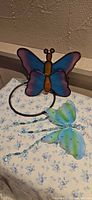 Wide view of stained glass butterfly suncatcher on ring with fabric butterfly ornaments