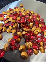 Loose oval fuchsia rhinestones showing foiled backs on metallic surface