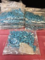Multiple sealed bags of turquoise half-dome earring parts