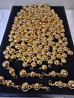 Full view of multiple strands of gold-tone beads on black background