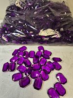 Clear bag filled with purple acrylic gems and several loose pieces displayed
