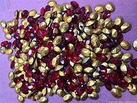 Pile of red oval crystals with gold backs spread on surface