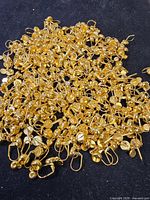 Large pile of gold-tone leverback earring findings displayed on black surface