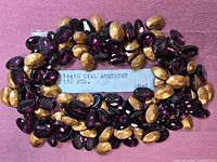 Pile of oval purple flatback rhinestones surrounding printed size/quantity label