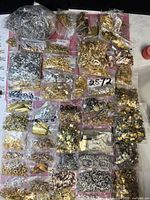 Bulk lot of small plastic bags containing assorted metal findings in various metallic finishes
