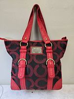 Front view showing logo pattern, red leather trim and handles