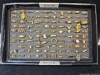 Full view of black tray containing rows of assorted gold-tone rings