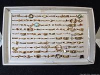 Full view of white tray containing rows of gold-tone costume rings