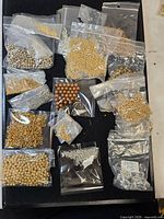 Overall lot showing multiple small bags of metallic and glass beads