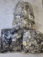 Three bags filled with metal case backs and plastic rings