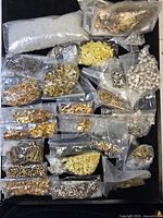 Overview of all clear bags filled with assorted metal components on black surface