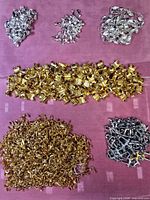 Six sorted piles of gold-tone, silver-tone and gunmetal jewelry findings on pink background