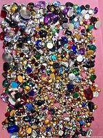 Full spread of assorted rhinestones and cabochons on pink background