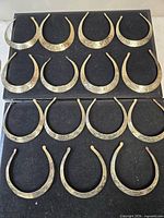 Full set of 16 etched brass silver-tone chokers laid out on black surface