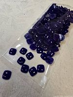 Full bag of cobalt blue square pillow glass beads spilling onto surface