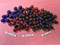 Full lot of multicolour swirled glass beads on pink cloth with Made in Japan labels