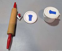 Rolling pin, metal pastry crimper, two plastic lids and ceramic mug laid out