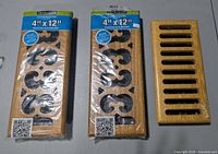 Two packaged scroll-style Decor Grates registers and one unpackaged slotted register