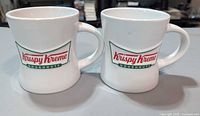 Front view of both Krispy Kreme mugs showing logos and overall condition