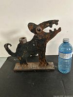 Front view of welded metal dog sculpture with water bottle for scale