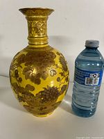 Full view of yellow porcelain vase beside water bottle for scale