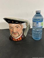 Front view of Henry VIII Toby Mug beside water bottle for scale