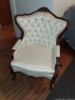 Front view showing tufted upholstery, carved crest and cabriole legs