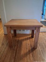 Side view of rectangular solid wood side table showing top and two legs.