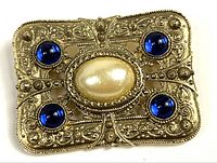 Front view showing faux pearl center, four blue stones, gold-tone filigree