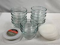 Stacks of twelve Cooking Concepts bowls with white lids and one Anchor Hocking bowl lid group shown