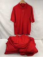 Stack of red polo shirts with one displayed on hanger