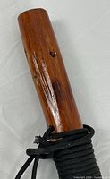 Handle end showing polished wood and cord wrap