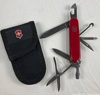 Knife open with multiple tools extended beside canvas pouch