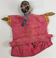 Full view of puppet showing pink silk jacket, wood arms, control rods
