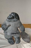 Front view of signed Inuit soapstone hunter holding tool and separate accessory