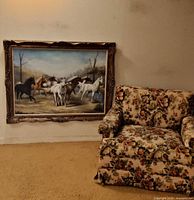 Painting leaning against wall beside floral armchair showing scale