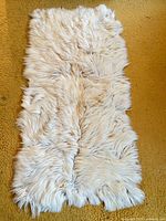 Full view of cream sheepskin rug on floor