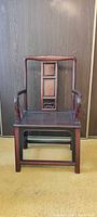 Front view of wooden armchair showing panel back, shaped arms, stretcher base
